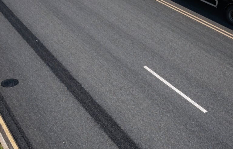 An aerial-angle shot of a logistics yard in the UK, showing clean asphalt and a recently completed, professional pothole repair that blends perfectly into the surface.