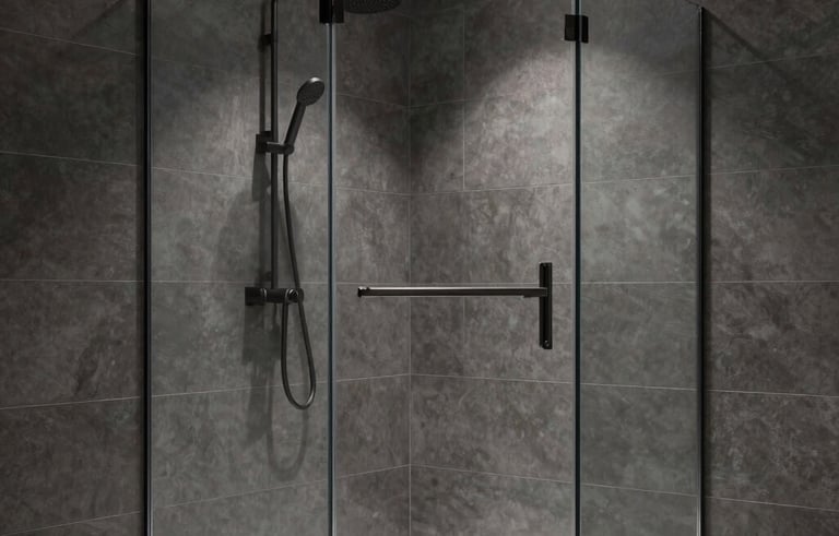 A minimalist walk-in shower with floor-to-ceiling clear glass panels and large format dark gray tiles. A matte black rain shower head and integrated lighting highlight the clean, architectural design in a modern home.