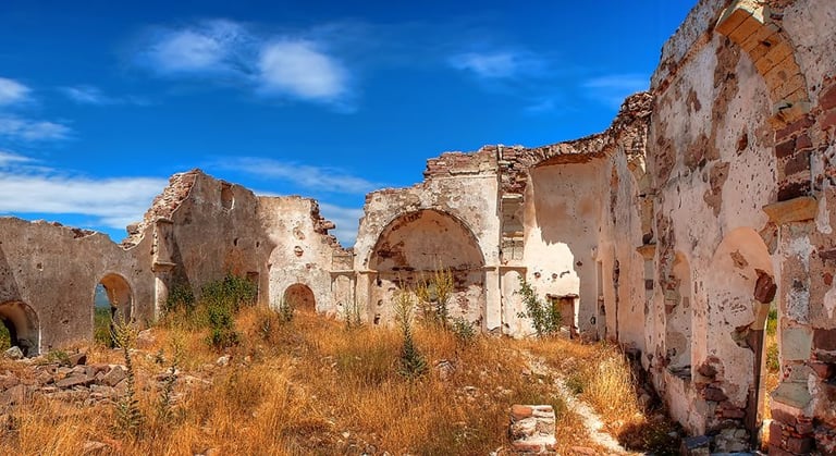 Under the blue sky, the ancient city of Erythrai, covered in dry grass.