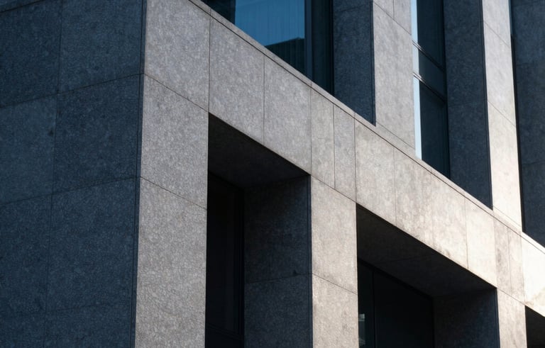 Minimalist architectural detail of a modern stone and glass structure in a North American city, conveying strength and permanence, with Slate Blue shadows and Platinum highlights.