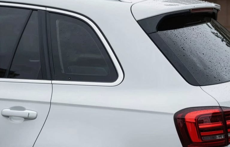 Close-up of a high-quality, custom-designed waterproof vinyl decal being applied to the rear window of a clean, modern white SUV parked in a North American driveway.