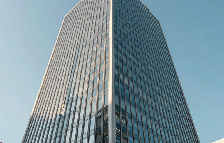 An architectural photograph of a sleek, contemporary glass office tower in a North American business district. The shot is taken from a low angle against a clear blue sky, emphasizing corporate success. Reflective surfaces show light blue and off-white tones.
