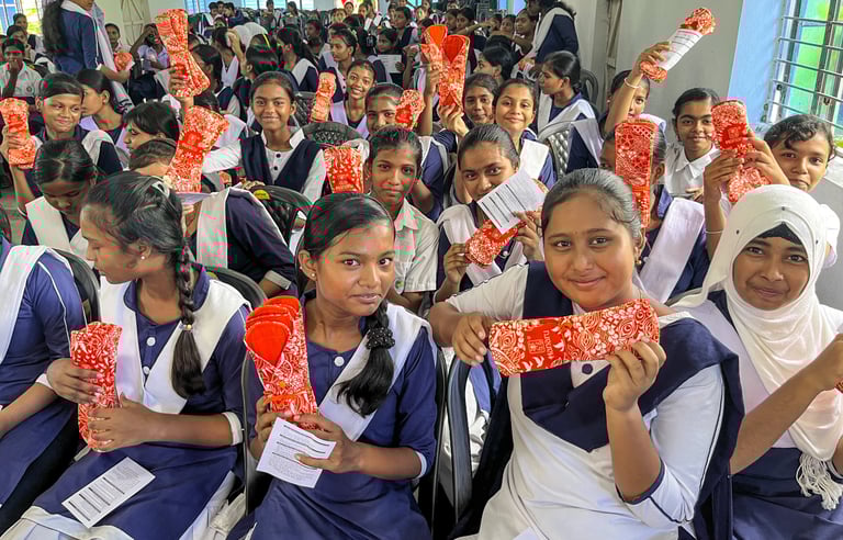 Large classroom of girls holding p washable napkin packs..