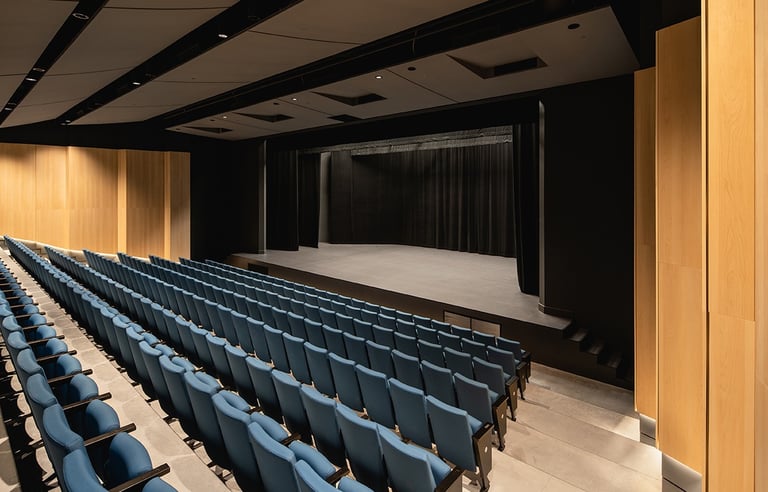 a theater stage with blue chairs and a stage