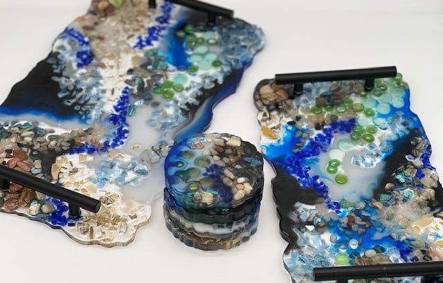 two trays with black handles, incorporating rock, shell, and glass design elements