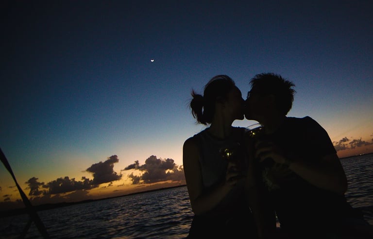 The photo shows a couple kissing on a sunset boat tour.