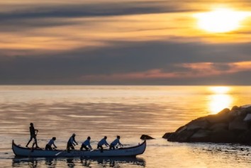 grupo de personas en barca remando en dirección a tierra firme