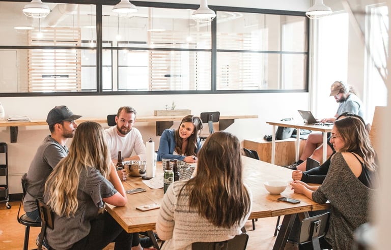 equipo joven dialogando en oficina alrededor de una mesa