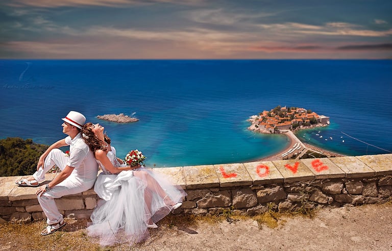 Bride and groom embracing at sunset on Budva beach with turquoise Adriatic Sea and coastal rocks in