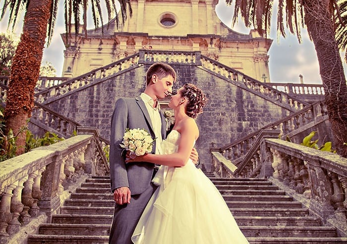 Bride and groom on grand stone staircase at historic church in Kotor, Montenegro, wedding ceremony p