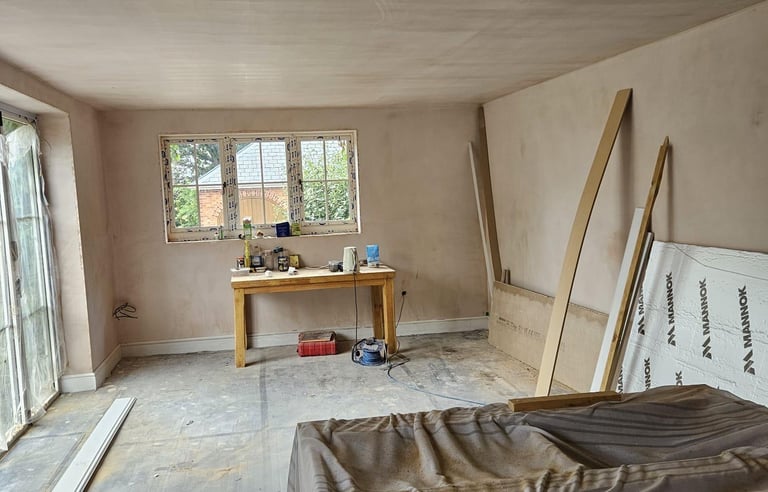 AN EMPTY ROOM THAT HAS BEEN PLASTERED AND A WINDOW
