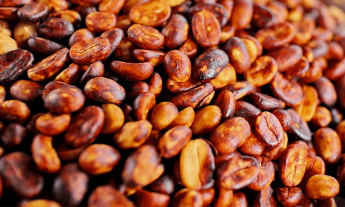 a pile of roasted beans on a wooden table
