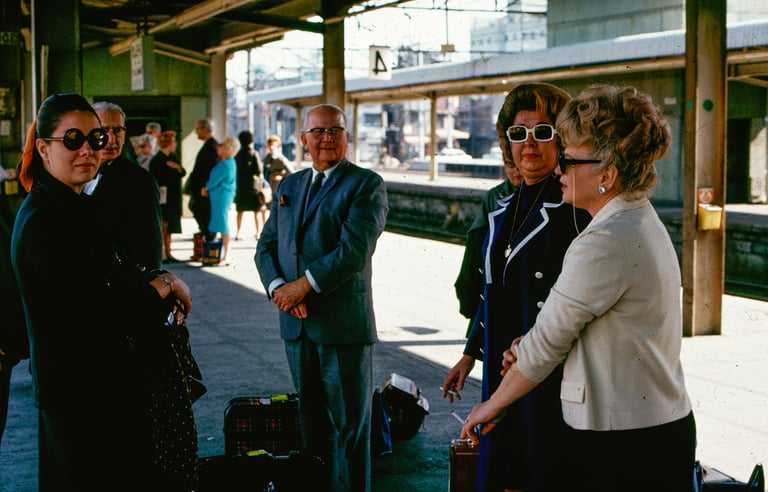 Vintage photo of stylish travelers wearing sunglasses at a train station platform in the 1960s.