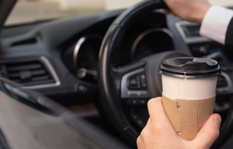 Client serein assis dans sa nouvelle voiture, tenant un café à la main.