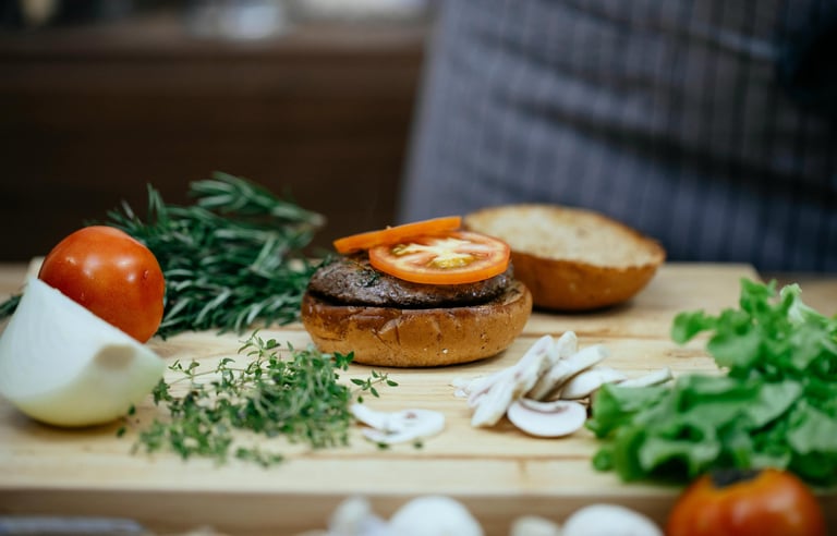 chef making a delicious burger with beef, tomato, mushrooms and onions.