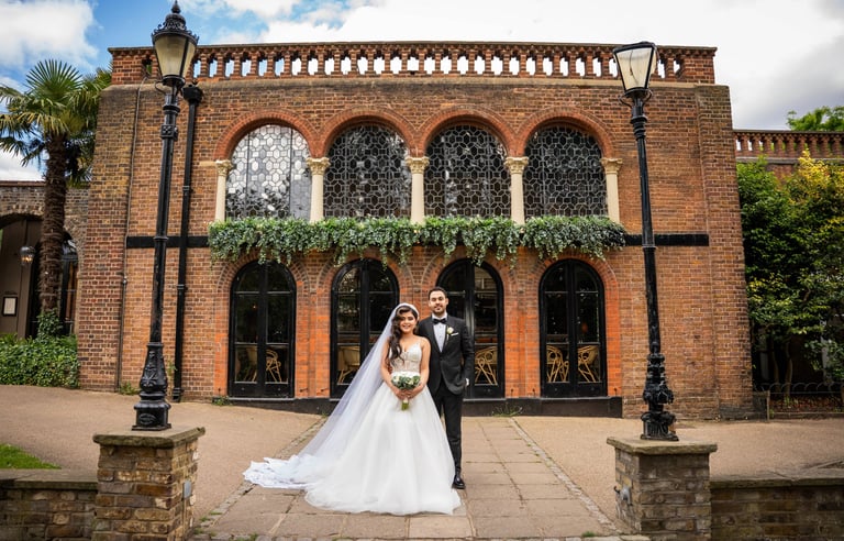 Bride and groom standing in front of a historic brick building, captured by Fred Art Studio.