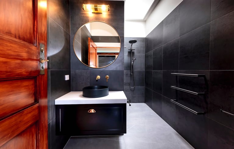 Modern black bathroom Renovation by Qualitas Builders, Auckland - sleek black tiling, round mirror