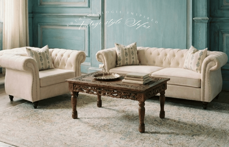 Vintage style tufted cream sofas and a carved wood coffee table in a rustic blue living room.