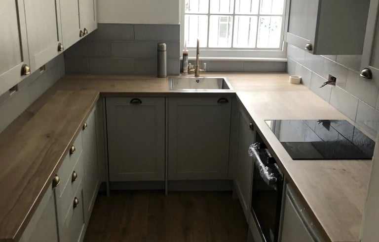 Contemporary kitchen with wooden worktops and fitted units in Brighton house renovation.