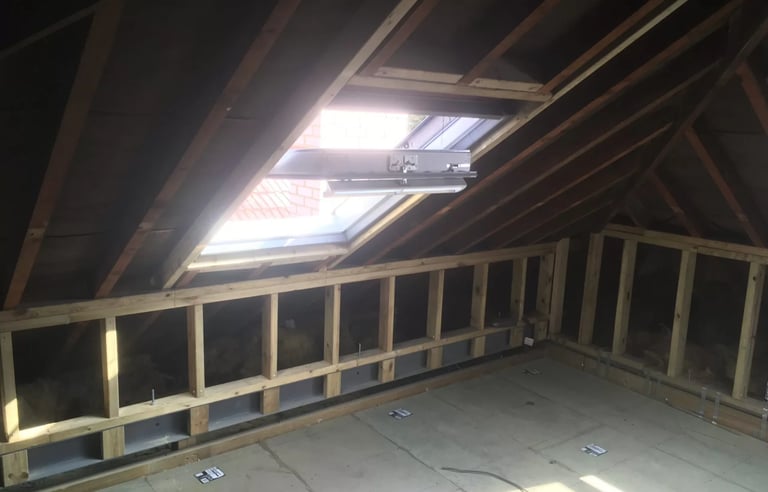 Loft conversion interior framing with roof window installation in Brighton property.