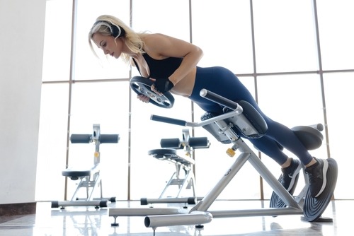 a woman in a sports bra top and headphones on a stationary bench