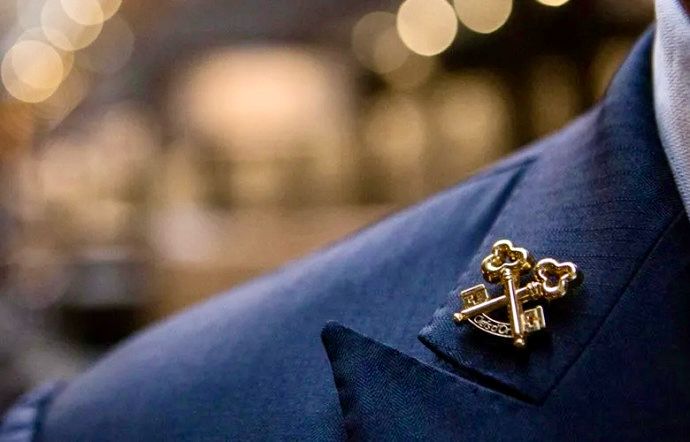 a man in a suit and tie with a gold anchor on it