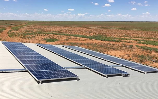 Solar panels installed on a metal roof overlooking a vast desert landscape for renewable energy.