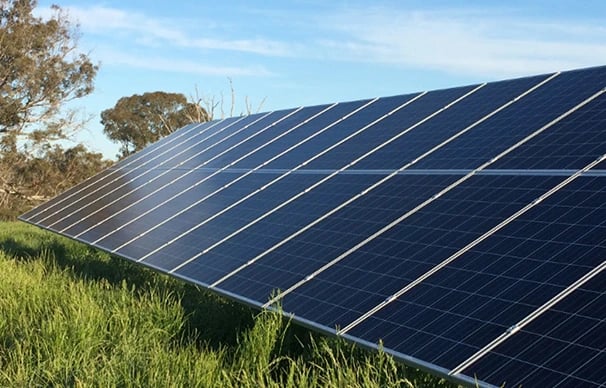Ground-mounted solar panel array installed in a green field for renewable energy generation.