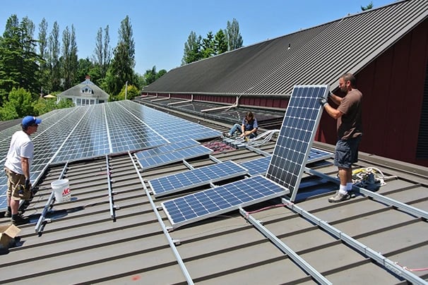 Professional contractors installing solar panels on a commercial metal roof for renewable energy.