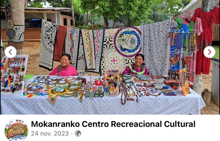 Two indigenous women selling handmade beaded jewelry and embroidered Shipibo textiles at an outdoor market.