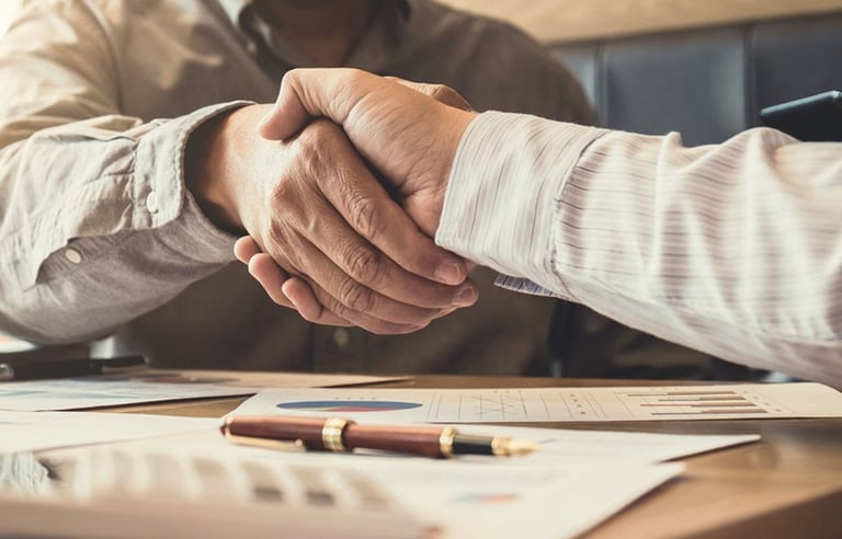 Image of a handshake across a desk between two men