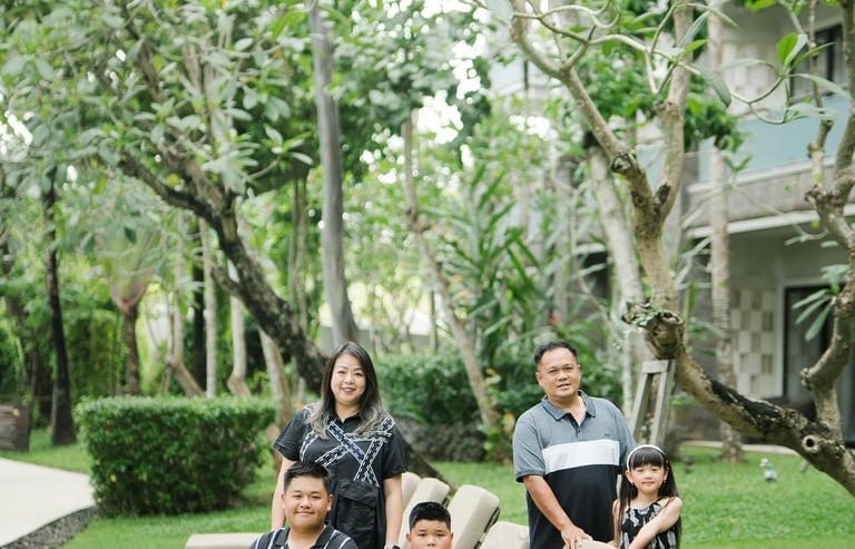 family photography at Movenpick Jimbaran Bali with parents and children sitting together on a green garden lawn