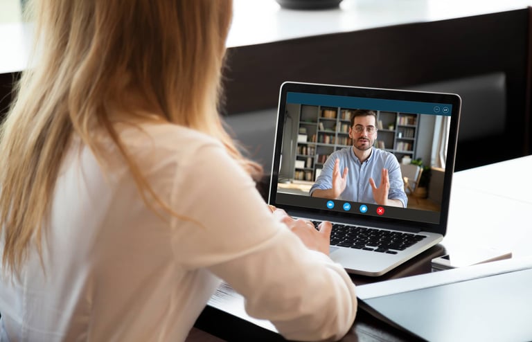 a woman sitting at a table with a laptop computer screen