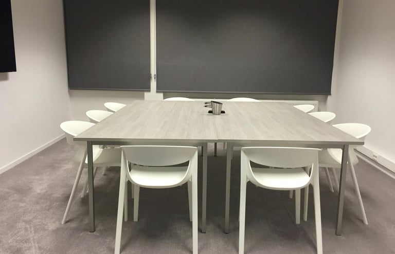 Lege lerarenkamer met tafel en stoelen. Stil beeld dat het gemis aan ontmoeting en leven symboliseer