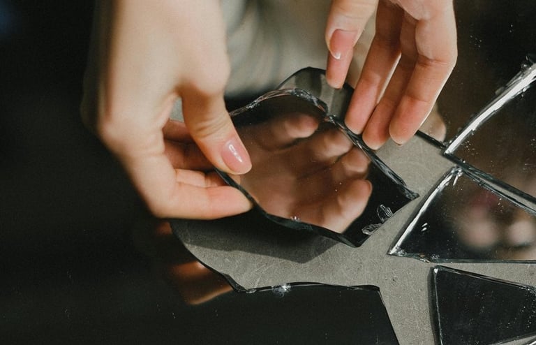 Hand pakt spiegelscherf op: reflectie komt stukje bij beetje, tot je het geheel ziet.