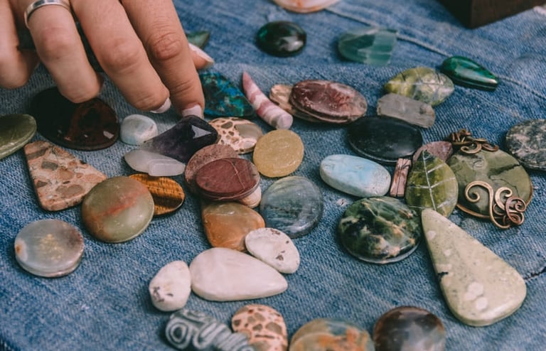 Una persona que selecciona piedras preciosas pulidas y cristales curativos sobre tela.