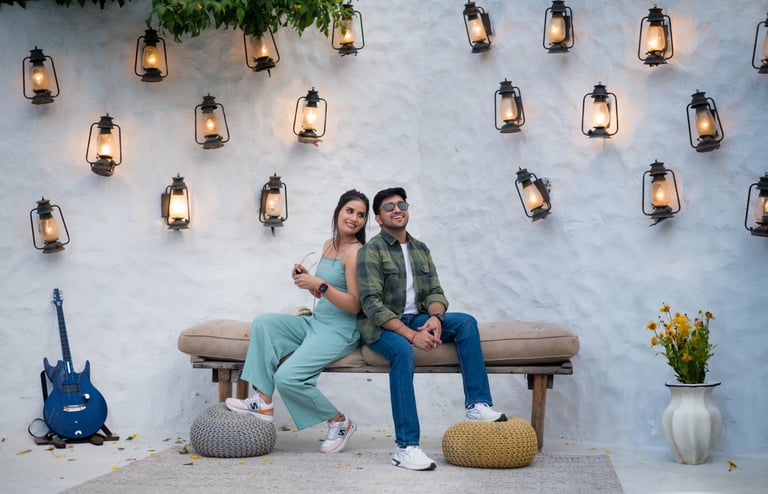 An outdoor photo shoot setting with a couple posing on a bench, with a guitar, and decorative lanter