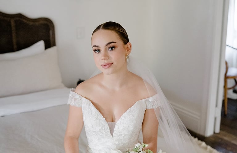 a bride in a white wedding dress sitting on a bed