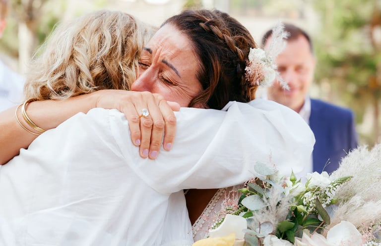 Photographie de mariée qui pleure de bonheur en serrant dans ses bras sa mère après la cérémonie de mariage, Talmont, Vendée