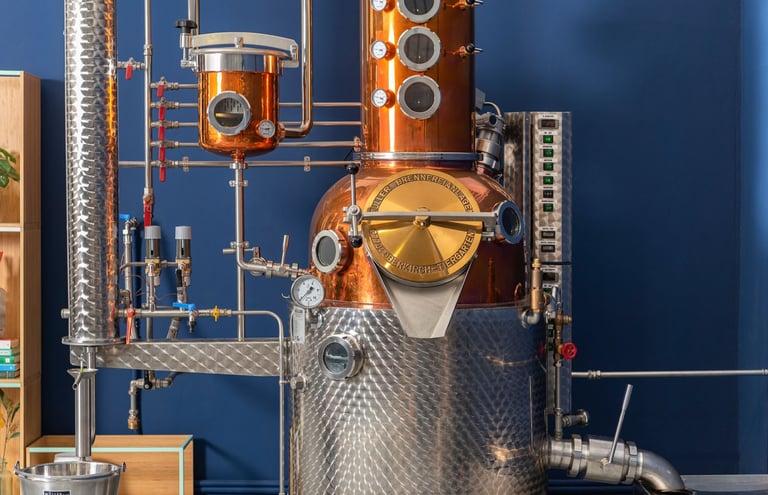 foto di un alambicco in rame e acciaio con tante tubature su sfondo blu