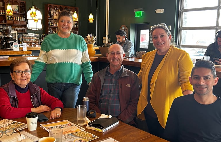 Group of smiling men and women at a table in a coffee house