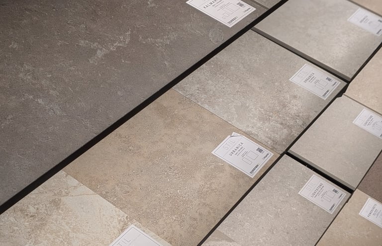 Display of various textured porcelain floor tiles in grey, beige, and stone finishes for home renovation.
