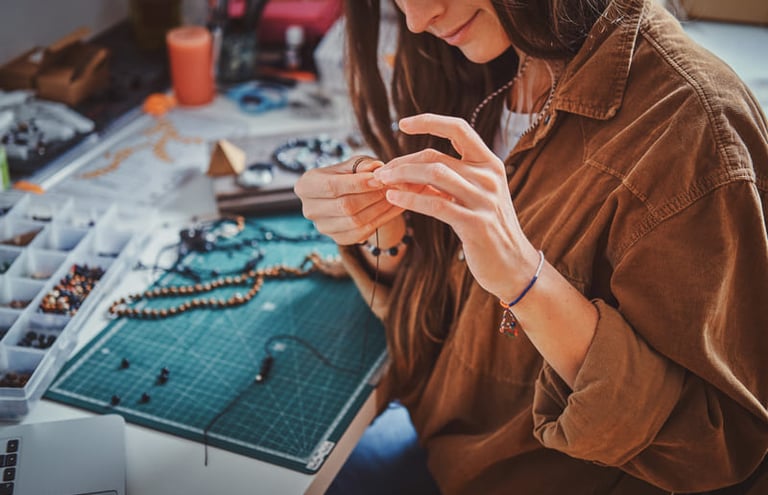 Una diseñadora de joyas elaborando un collar artesanal con cuentas en una estación de trabajo