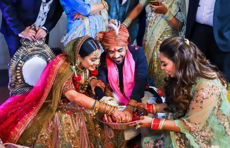 A bride and groom participate in a wedding ritual, their hands together over a bowl, while a woman s