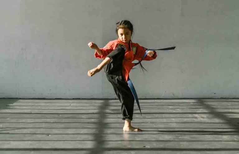 a woman in a red shirt and black pants is doing a karate pose