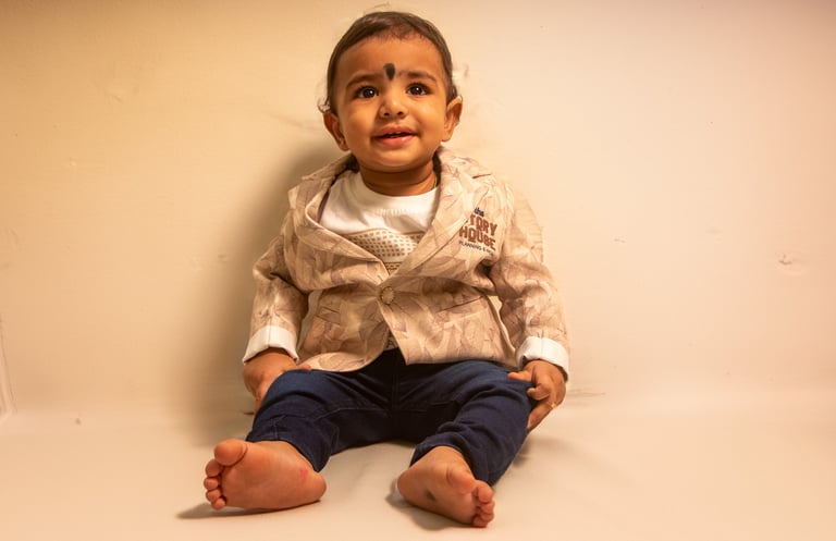 a baby sitting on a white surface with a white background