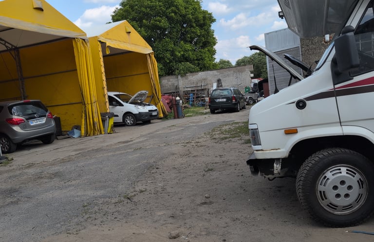 Campervan parked in a dusty auto repair lot in a small Polish town,