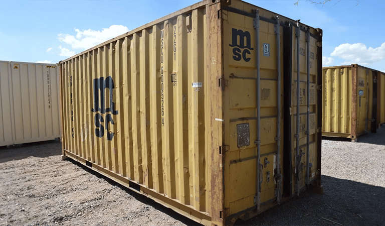 A yellow cargo worthy high cube shipping container with some dents dings rust wind and water tight
