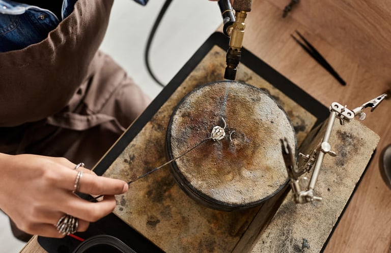 Joyero utilizando un soplete de gas para soldar un anillo de plata sobre un bloque de soldadura