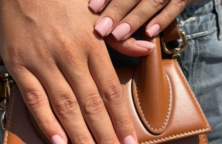 a woman's hands with a brown leather handbag